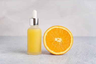 Bir şişe gerekli yağ ve açık arkaplanda olgun turuncu.