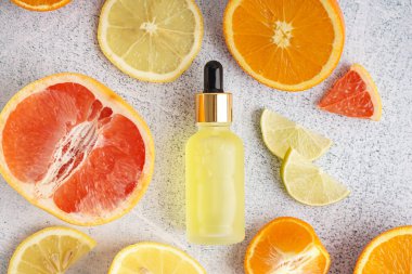 Temel yağ şişesi ve hafif arka planda taze narenciye meyvesi bileşimi
