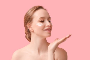 Pembe arka planda kremalı güzel genç bir kadın.