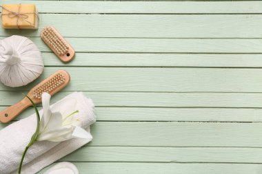 Yeşil ahşap arka planda banyo malzemeleri ve bitkisel poşetlerle güzel bir kompozisyon.