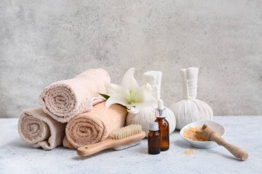 Havlular, bitkisel poşetler, serum şişeleri ve grunge arkaplanda bir kase deniz tuzu olan güzel bir spa kompozisyonu.