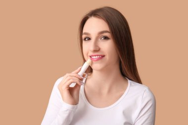 Bej arka plana dudak kremi süren genç bir kadın.