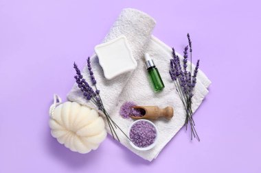 Deniz tuzu, bir şişe lavanta yağı ve leylak arkaplanda banyo süngeri ile güzel bir kompozisyon.