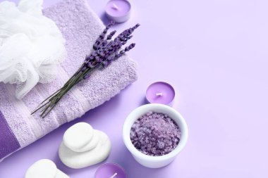 Havlu, deniz tuzu, lavanta çiçeği ve leylak arkaplanlı spa taşlarıyla güzel bir kompozisyon.