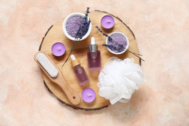 Ahşap tepsi, deniz tuzu ve pembe grunge arka planda bir şişe lavanta yağıyla güzel bir kompozisyon.