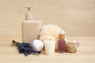 Lavanta çiçekleri, banyo bombası, mumlar, ahşap arka planda bir şişe kozmetik yağ ve banyo süngeri.