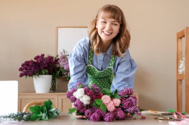 Çiçekçide leylaklar ve güllerle güzel çiçekler yapan kadın çiçekçi.