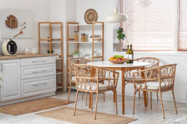 Yemek masası, raf ünitesi, sandalye ve lamba olan şık bir mutfak.