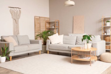 Gri kanepeleri ve çiçekleri olan modern bir oturma odası.