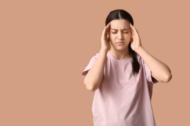 Bej arka planda baş ağrısı çeken güzel bir genç kadın.