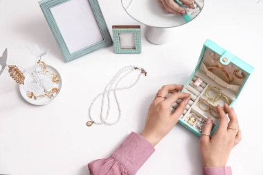 Masanın yanında farklı takılarla dolu bir kutusu olan genç bir kadın.