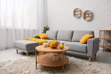 Gri kanepeli, portakallı, sehpalı ve yastıklı bir oturma odası.