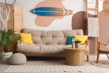 Gri kanepesi, merdiveni, sehpası ve sörf tahtası olan şık bir oturma odası.