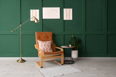 Konforlu koltuk, sehpa ve oturma odasındaki duvarda resimler.