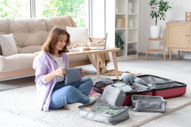 Evde bavul hazırlayan genç bir kadın. Seyahat kavramı