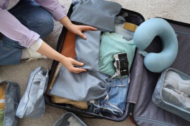 Evde bavul hazırlayan genç bir kadın. Seyahat kavramı