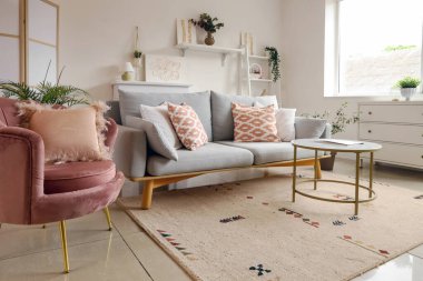 Konforlu kanepe, koltuk, sehpa ve oturma odasında resimler.