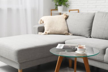 Rahat bir kanepe, kahve masası, dergi ve oturma odasında çay.