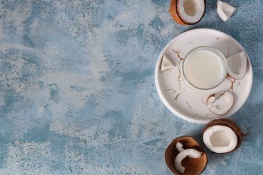 Beyaz tepsi ve mavi grunge arka planda taze hindistan cevizi sütü.