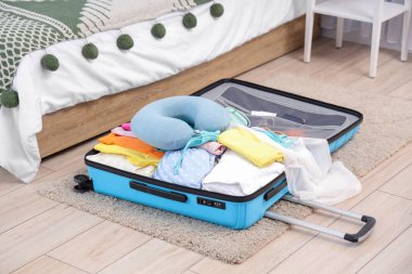 Yatak odasında plaj aksesuarlarıyla dolu bir bavul. Seyahat kavramı