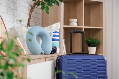 Bavul, çekmece çekmecesinin yanında boyun yastığı ve plaj çantası odada. Seyahat kavramı