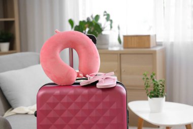 Odadaki bavulda boyun yastığı ve parmak arası terlikler. Seyahat kavramı