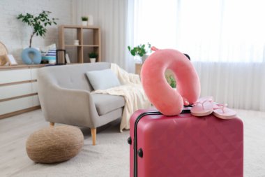 Odadaki bavulda boyun yastığı ve parmak arası terlikler. Seyahat kavramı