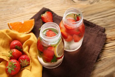 Çilekli ve ahşap arka planda limonlu su şişeleri.