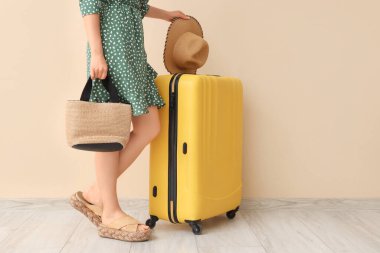 Bavullu, çantalı ve şapkalı genç bir kadın.