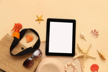 Bej arka planda çantalı ve güneş gözlüklü tablet ve plaj aksesuarları. Üst görünüm