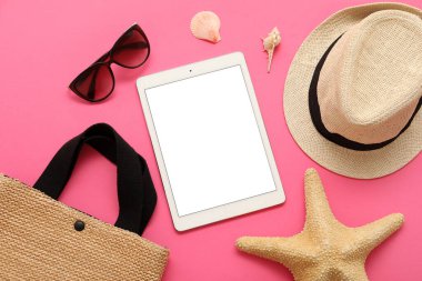 Tablet ve plaj aksesuarları, pembe arka planda güneş gözlüğü ve şapka. Üst görünüm