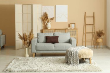 Oturma odasındaki kanepenin yanında kuru kamışlı vazo.