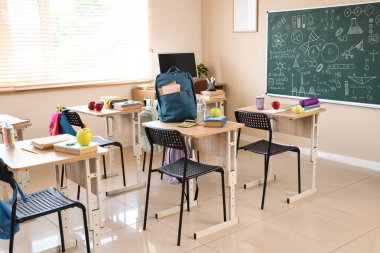 Boş sınıfta elmalı masalar ve okul kağıtları