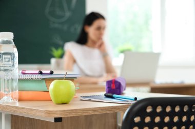 Sınıfta masa başında kitap ve su şişesi olan elma, yakın plan.