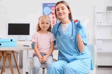 Tiroit bezi modeli olan bir kadın endokrinolog ve klinikte küçük bir kız.