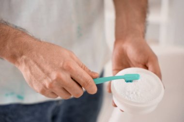 Banyoda diş pudrası ve fırçası olan genç adam, yakın plan.