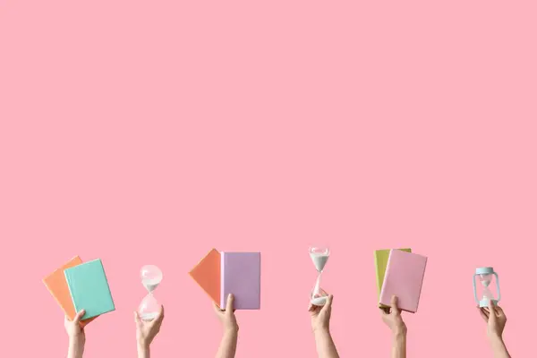 stock image Female hands holding hourglasses and books on pink background