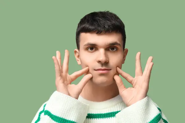 stock image Young deaf mute man using sign language on green background