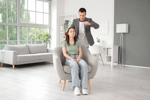 stock image Young woman sitting in armchair during hypnosis session at psychologist office