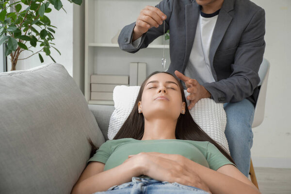 Молодая женщина лежит на диване во время сеанса гипноза в кабинете психолога