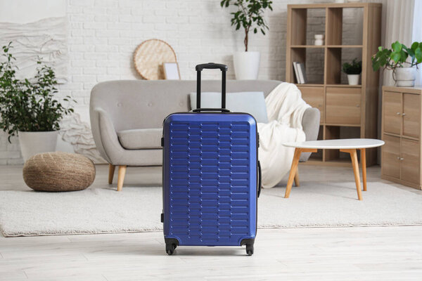 Упакованный синий чемодан в интерьере гостиной