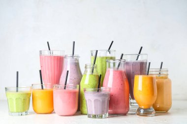 Beyaz arka planda farklı taze smoothie bardakları ve şişeleri