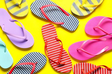 Sarı arka planda farklı tarz parmak arası terlikler.