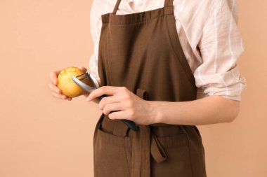 Kahverengi arka planda çiğ patates soyan kadın.