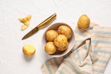Beyaz arka planda çiğ patates ve bıçaklı kase.