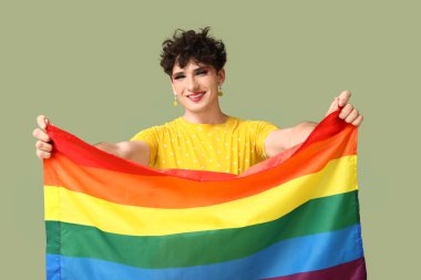 Yeşil arka planda LGBT bayrağı olan genç transseksüel kadın.