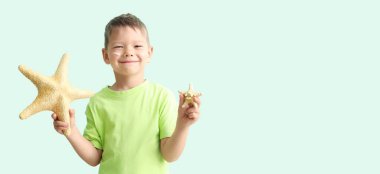 Yüzünde deniz yıldızları ve güneş kremi olan küçük bir çocuk.