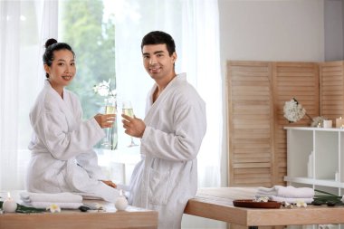 Spa salonunda şampanya bardakları olan genç bir çift.