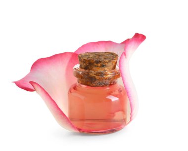 Beyaz arka planda gül özü ve taç yaprağı olan bir şişe kozmetik yağı.