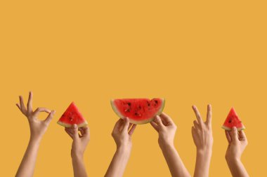 Sarı arka planda olgun karpuz dilimleriyle kadın elleri.